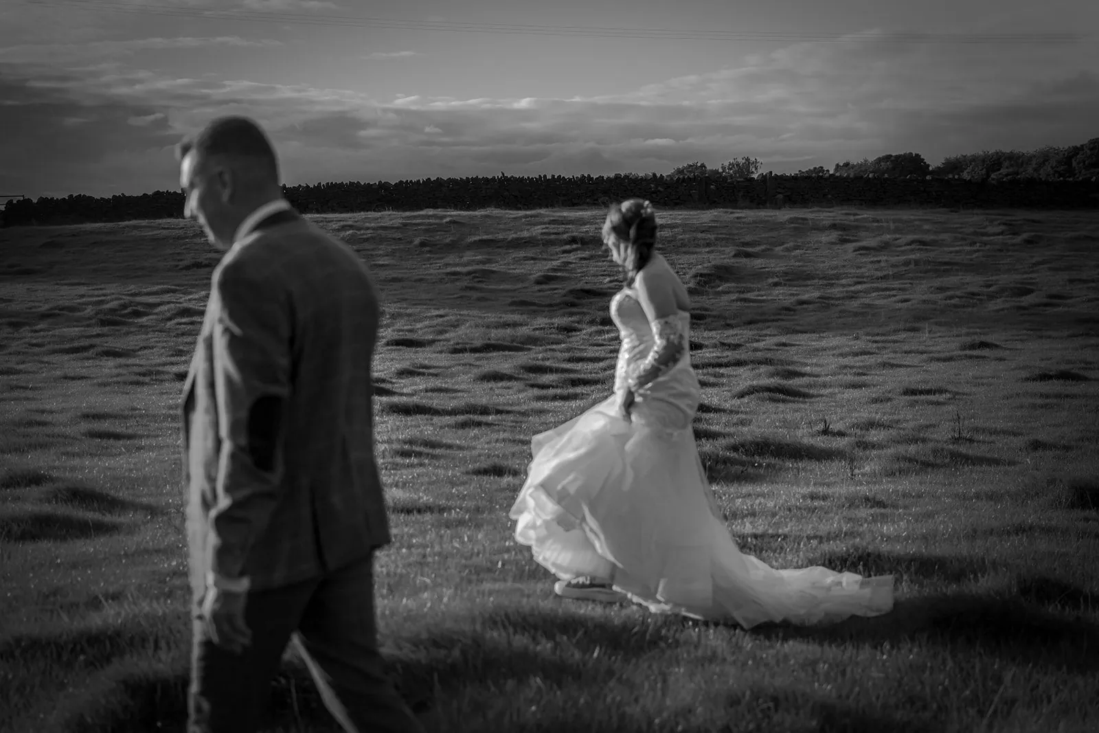 Black and white photograph of a couple in a field at dusk below Longridge Fell