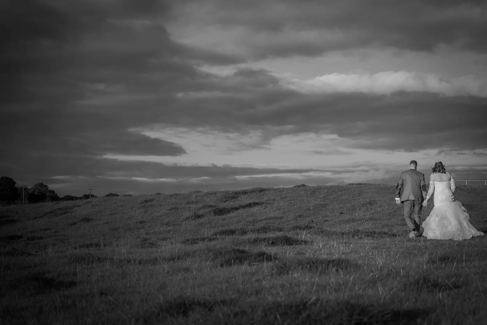Wide black and white portrait of a couple with Ribble Valley hills behind them