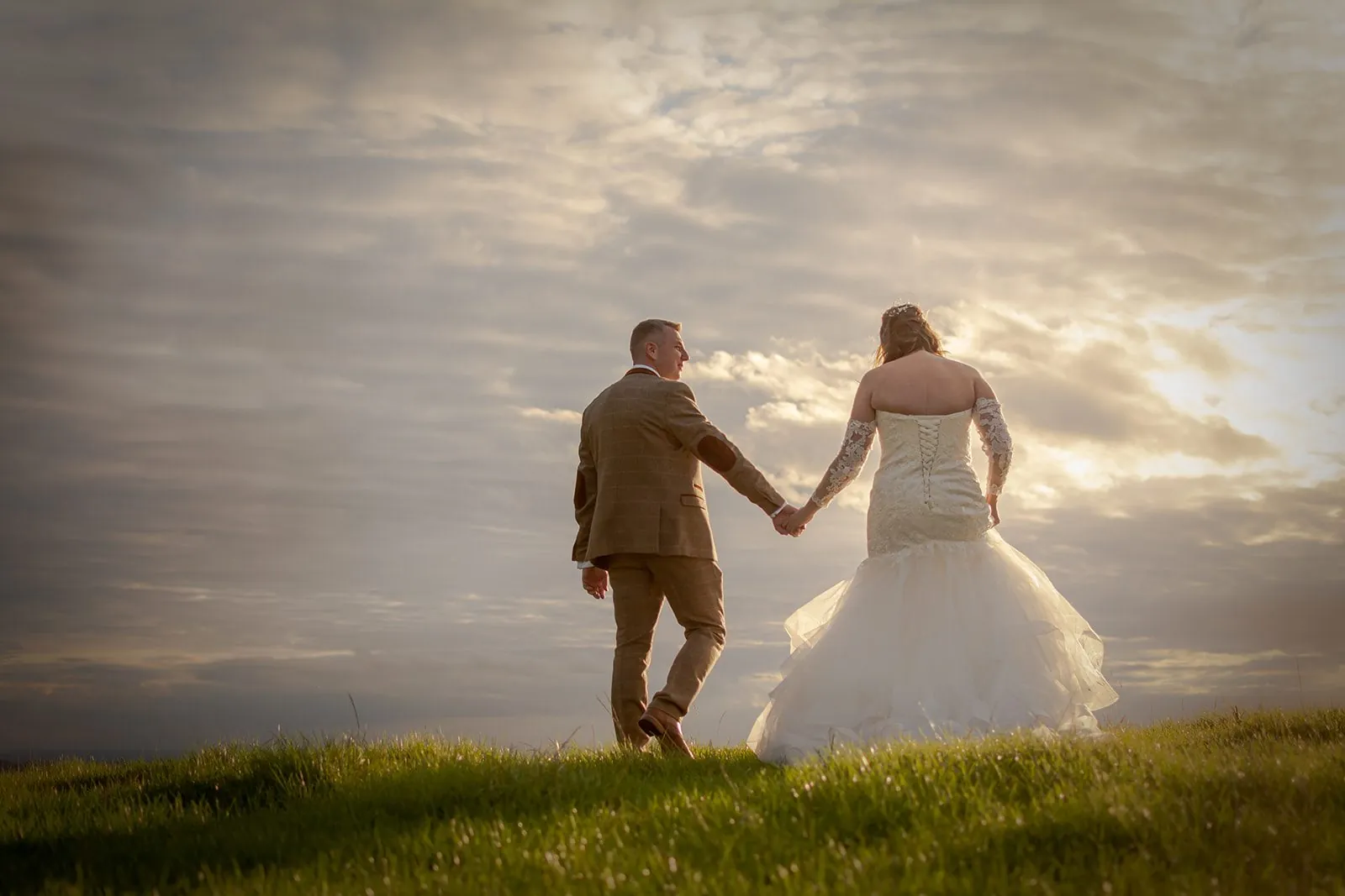 Couple on a hilltop with the sun dropping behind them